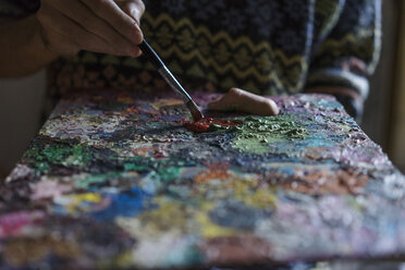 Männlicher Künstler mischt Ölfarbe auf einer Palette im Künstleratelier, Nahaufnahme Detail - CUF02746