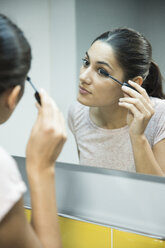 Woman applying mascara in front of mirror - CUF02789