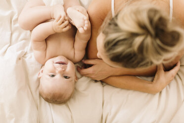 Overhead-Porträt von niedlichen Baby-Mädchen auf dem Bett liegend mit Mutter - CUF02794