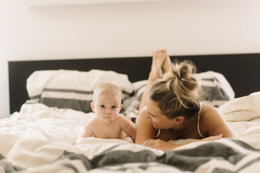 Portrait of baby girl lying on bed with mother - CUF02796