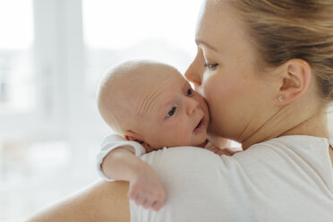 Young woman kissing baby daughter on cheek, over shoulder view - CUF02861