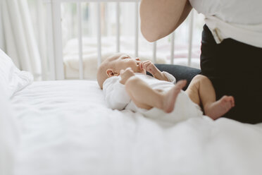 Young woman sitting on bed with baby daughter, cropped - CUF02862