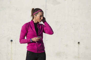 Portrait of woman wearing earphones holding smartphone - CUF02882