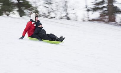 Mother and son sledding on snowy hill - CUF02920
