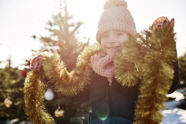 Girl in christmas tree forest wearing tinsel, portrait - CUF02924