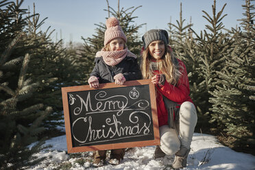 Mädchen und Mutter im Weihnachtsbaumwald mit Frohe-Weihnachten-Schild, Porträt - CUF02928