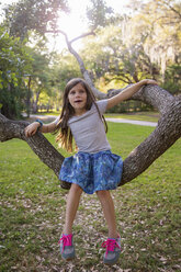 Portrait of girl, outdoors, sitting on tree branch - CUF02942