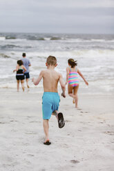 Mann und Kinder laufen vom Strand zum Meer, Rückansicht, Dauphin Island, Alabama, USA - CUF02962
