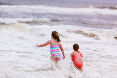 Zwei Mädchen spielen in den Meereswellen, Rückansicht, Dauphin Island, Alabama, USA - CUF02965