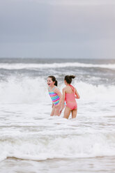 Zwei Mädchen stehen in den Wellen des Ozeans, Dauphin Island, Alabama, USA - CUF02966