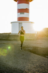 Young female runner running on coastal dirt track at sunset - CUF02968