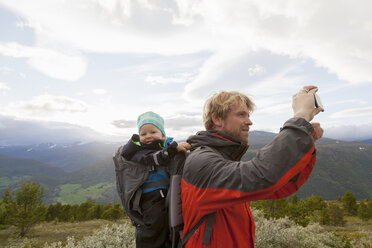 Männlicher Wanderer mit Sohn beim Fotografieren der Berglandschaft, Jotunheimen-Nationalpark, Lom, Oppland, Norwegen - CUF03002