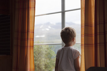 Junge schaut durch ein Fenster mit Vorhängen - CUF03007