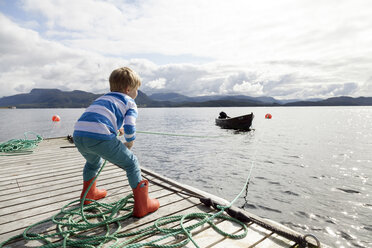 Junge auf Pier, der ein Fjordboot an einem Seil zieht, Aure, More og Romsdal, Norwegen - CUF03014