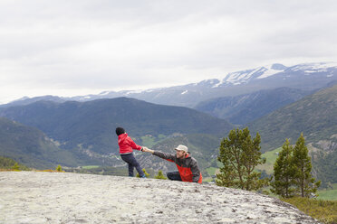 Boy helping hiker father over rock in mountain landscape, Jotunheimen National Park, Lom, Oppland, Norway - CUF03018