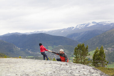 Junge hilft Wandervater über Felsen in Berglandschaft, Nationalpark Jotunheimen, Lom, Oppland, Norwegen - CUF03018