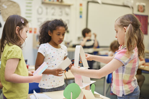 Drei Grundschülerinnen basteln eine Papierpyramide im Klassenzimmer - CUF03030
