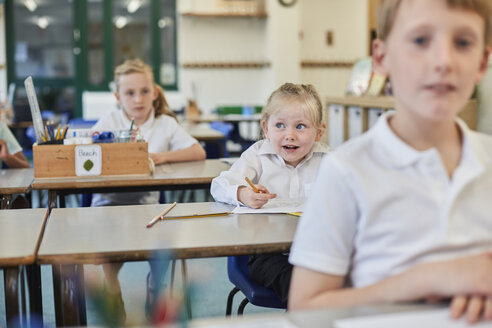 Grundschulmädchen und -junge machen Schularbeiten an den Schulbänken - CUF03034