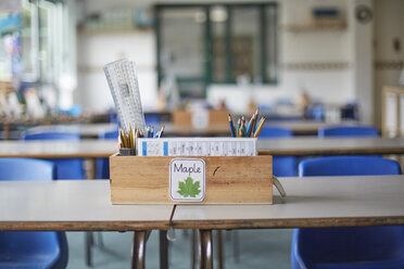 Schreibtisch im Klassenzimmer mit Holzkiste voller Bleistifte und Lineale in einem Grundschulklassenzimmer - CUF03041