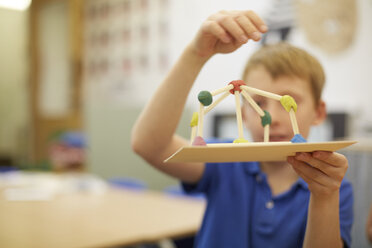 Schüler bastelt Ball- und Stockmodell im Klassenzimmer einer Grundschule - CUF03042