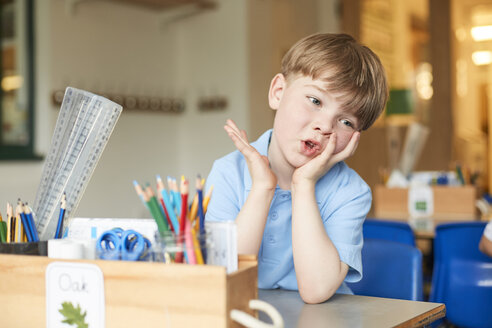 Gelangweilter Grundschüler am Schreibtisch im Klassenzimmer - CUF03056