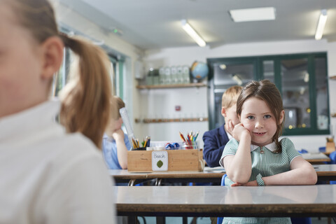 Porträt einer Schülerin, die an der Schulbank einer Grundschule sitzt, lizenzfreies Stockfoto