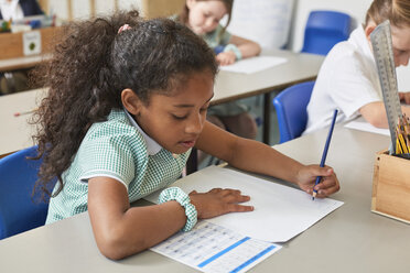 Schülerin beim Schreiben am Schreibtisch in der Grundschule - CUF03059