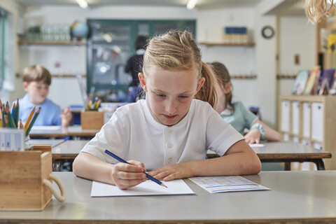 Schülerin beim Schreiben im Unterricht in der Grundschule, lizenzfreies Stockfoto