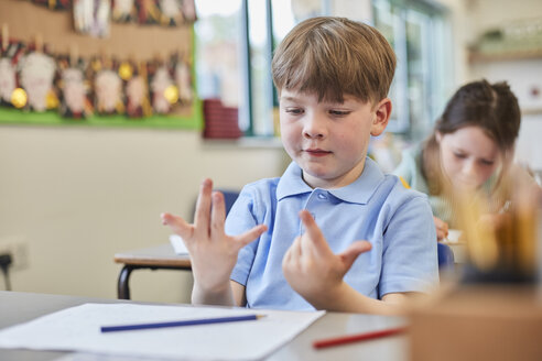 Schuljunge zählt mit den Fingern im Unterricht in der Grundschule - CUF03068