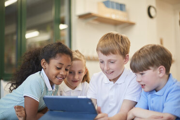 Jungen und Mädchen betrachten ein digitales Tablet im Klassenzimmer einer Grundschule - CUF03075