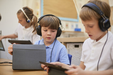 Schüler und Mädchen hören im Unterricht in der Grundschule Kopfhörer - CUF03084