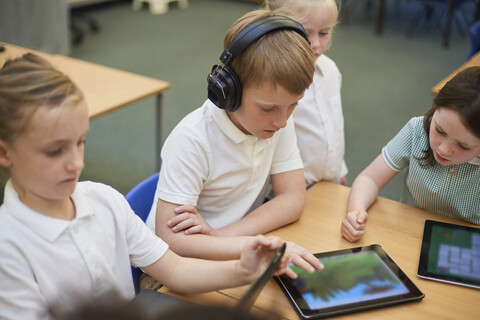 Jungen und Mädchen betrachten digitale Tablets im Unterricht der Grundschule, lizenzfreies Stockfoto