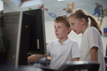 Schoolboy and girl using computer in classroom at primary school - CUF03095