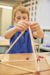 Schüler bastelt Ball- und Stockmodell im Klassenzimmer einer Grundschule - CUF03099