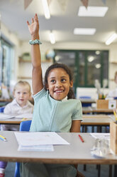 Schoolgirl with hand up in classroom at primary school - CUF03107