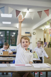 Schuljunge mit erhobener Hand im Klassenzimmer einer Grundschule - CUF03108