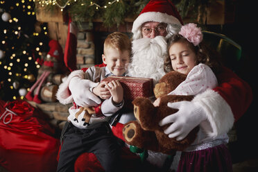 Young girl and boy visiting Santa, holding gifts - CUF03127