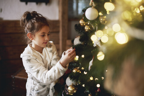 Junges Mädchen beim Schmücken des Weihnachtsbaums, lizenzfreies Stockfoto