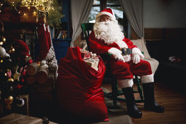 Portrait of Santa Claus, sitting in chair with sack full of presents - CUF03136