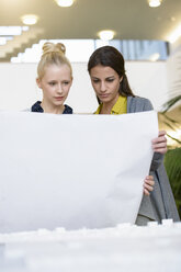 Colleagues discussing town planning drawings in office - CUF03250