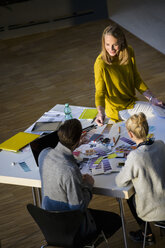 Male and female designers discussing colour swatches on design studio table - CUF03264