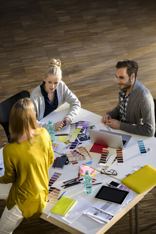 Männliche und weibliche Designer besprechen Farbmuster auf einem Tisch im Designstudio, lizenzfreies Stockfoto
