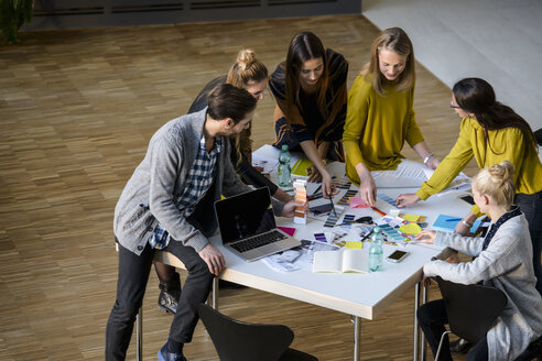 Ein Team aus männlichen und weiblichen Designern bespricht Farbmuster auf einem Tisch im Designstudio - CUF03270