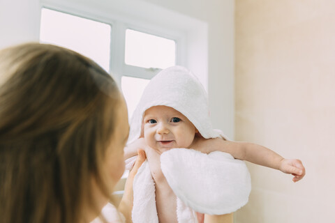 Mutter hält ihre kleine Tochter in ein Handtuch gewickelt, lizenzfreies Stockfoto