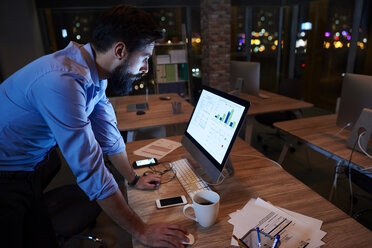 Young businessman working at computer on office desk at night - CUF03310