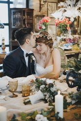Braut und Bräutigam sitzen am Tisch beim Hochzeitsempfang - CUF03341