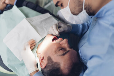 Dentist looking into male patient's mouth, elevated view - CUF03345