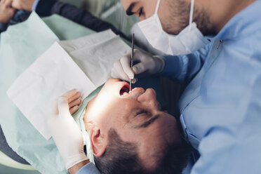 Zahnarzt schaut in den Mund eines männlichen Patienten, Ansicht von oben - CUF03345