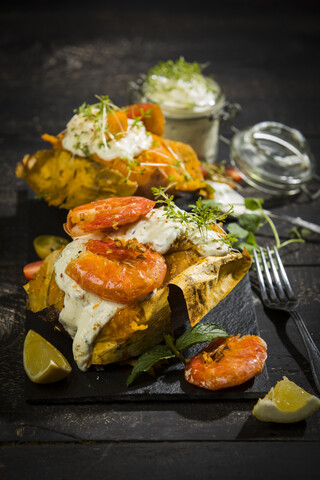 Gebackene Kartoffel, Süßkartoffel, argentinische rote Garnele, Sauerrahm auf Schiefer, lizenzfreies Stockfoto
