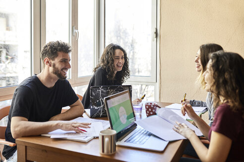 Four happy students at desk learning together - JRFF01619